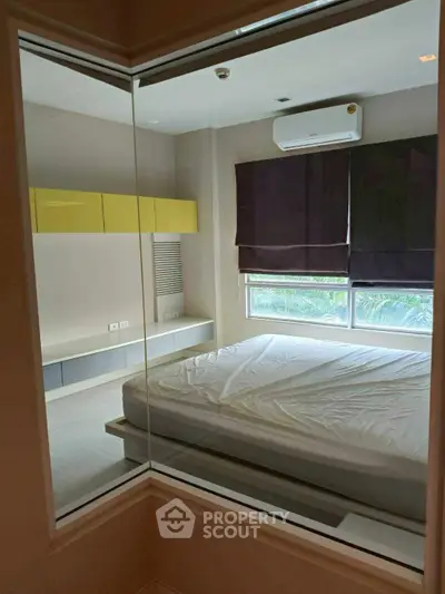 Modern bedroom with large window and air conditioning, featuring sleek built-in storage and minimalist design.