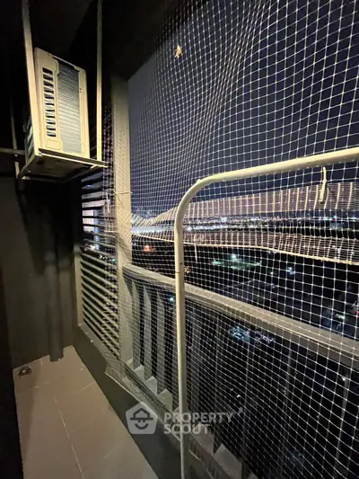 Cozy balcony with city view, featuring safety netting and air conditioning unit.