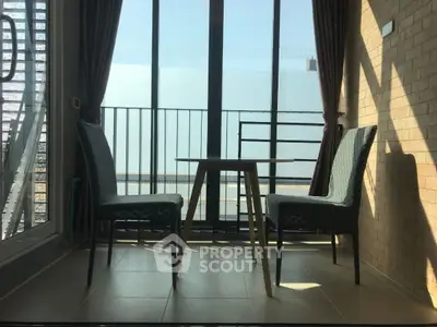 Cozy balcony with seating area and large glass doors, perfect for relaxation.