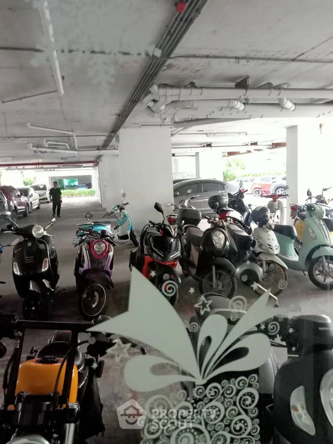 Spacious parking area with multiple motorcycles and cars in a covered garage.