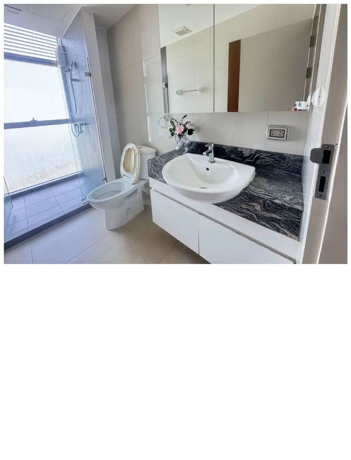 Modern bathroom with sleek fixtures and large shower area, featuring elegant marble countertop and stylish mirror.