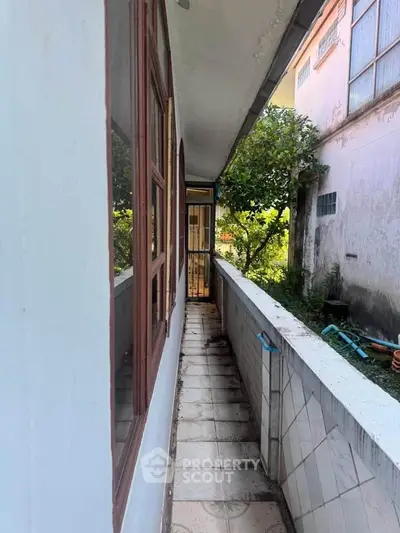 Charming narrow balcony with garden view in cozy residential property.