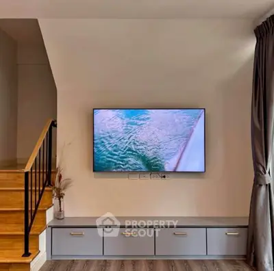 Modern living room with sleek TV setup and stylish staircase