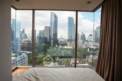 Luxurious bedroom with stunning city skyline view through floor-to-ceiling windows.