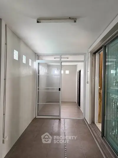 Spacious corridor with sliding glass doors and tiled flooring in modern apartment.