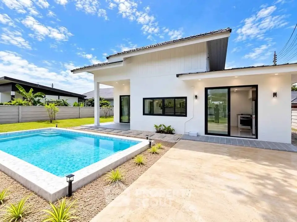 Modern white house with sleek pool and spacious patio under a clear blue sky.