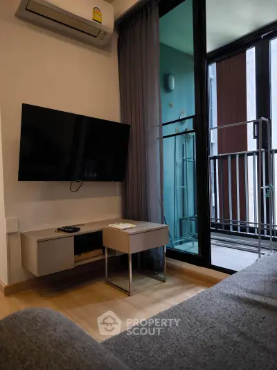 Modern living room with wall-mounted TV and balcony access in stylish apartment.
