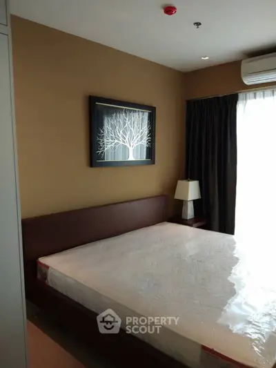 Modern bedroom with elegant decor and natural light, featuring a stylish framed artwork above the bed.