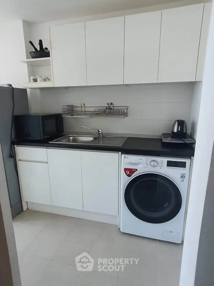 Modern kitchen with sleek white cabinets and built-in washing machine