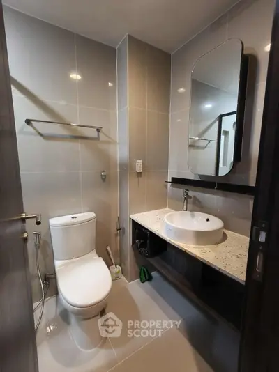 Modern bathroom with sleek fixtures and elegant design, featuring a large mirror and stylish sink.