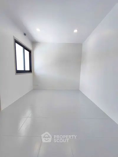 Spacious empty room with large window and bright lighting, perfect for customization.