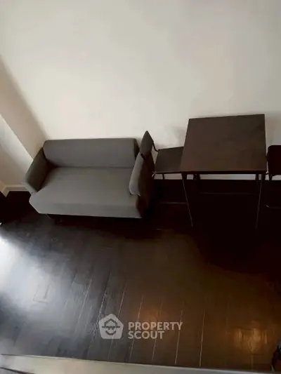 Modern minimalist living room with sleek dark flooring and compact furniture arrangement.