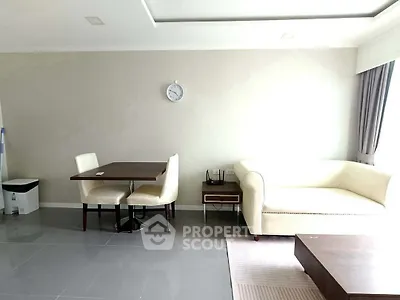 Modern living room with elegant white sofa and dining area, featuring sleek tile flooring and natural light.
