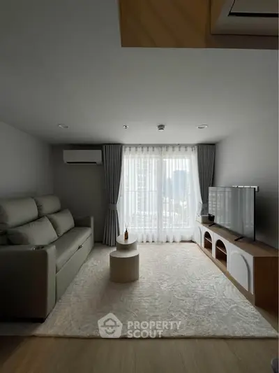 Modern living room with large window, cozy sofa, and sleek TV setup in a stylish apartment.