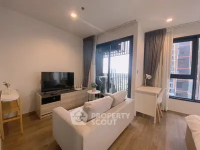 Modern living room with balcony view, stylish furniture, and ample natural light.