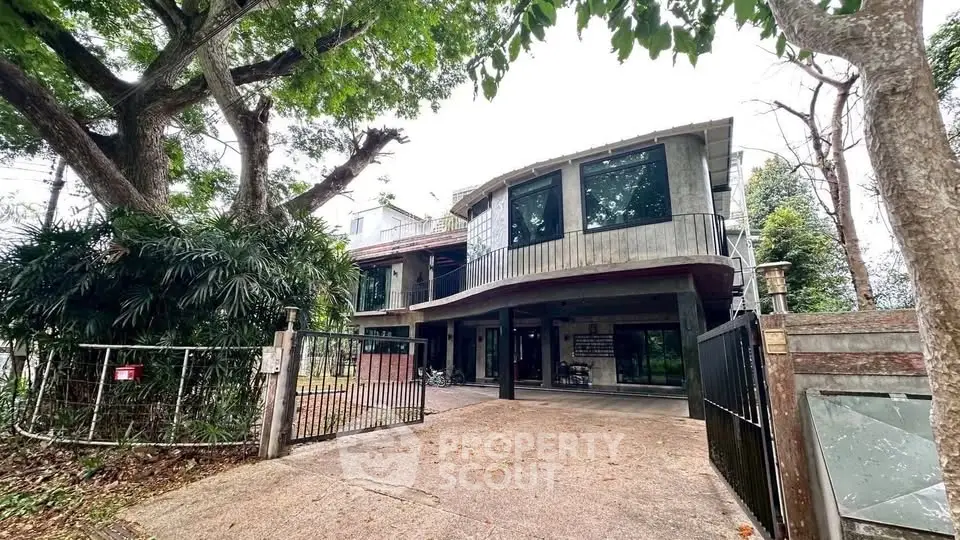 Stunning modern house with unique architecture and spacious driveway surrounded by lush greenery.