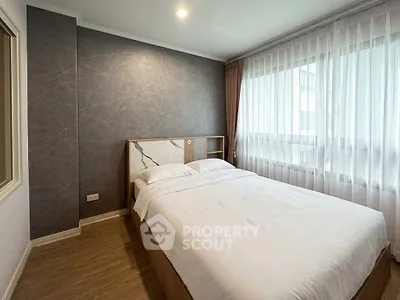 Modern bedroom with elegant decor and large window in a stylish apartment.