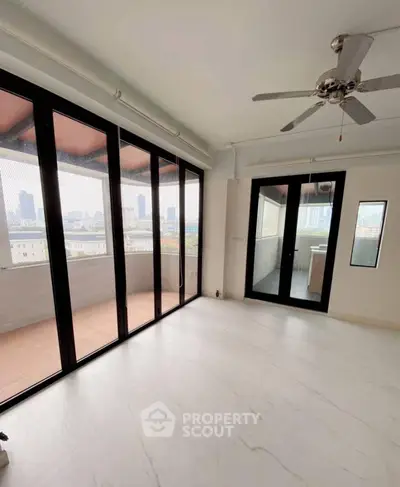 Spacious living room with large windows and balcony offering stunning city views.