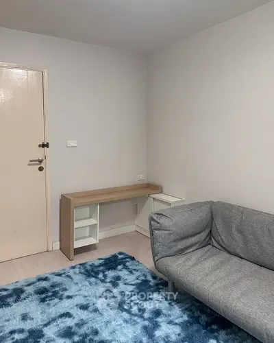 Cozy living room with modern gray sofa and stylish blue rug, perfect for relaxation.