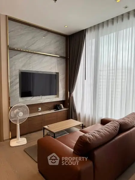 Modern living room with sleek design, featuring a brown leather sofa and large TV.