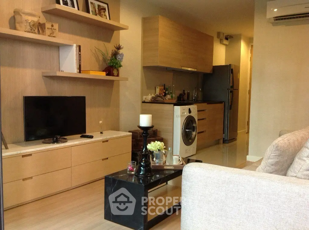 Modern living room with integrated kitchen featuring sleek appliances and stylish decor.