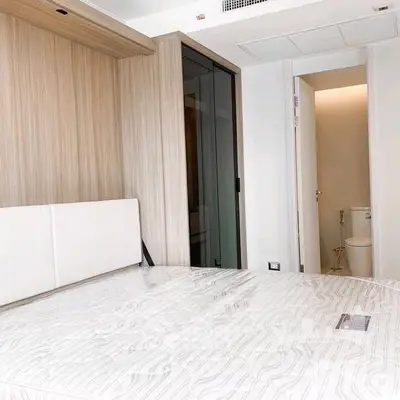Modern bedroom with wooden accents and ensuite bathroom in luxury apartment.