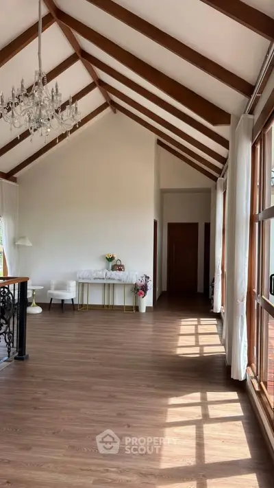 Spacious living room with high ceilings and elegant chandelier, featuring large windows for natural light.