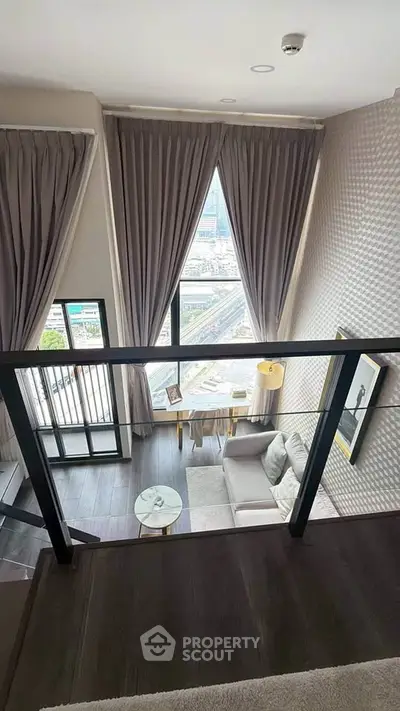 Luxurious loft-style living room with floor-to-ceiling windows and stunning city view.
