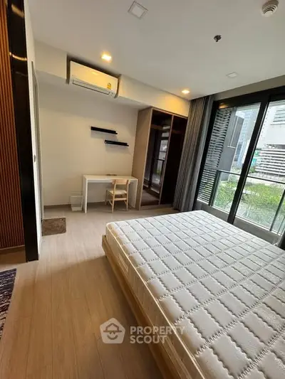 Modern bedroom with large window and balcony access in urban apartment