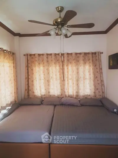 Cozy bedroom with double beds and ceiling fan, perfect for relaxation.