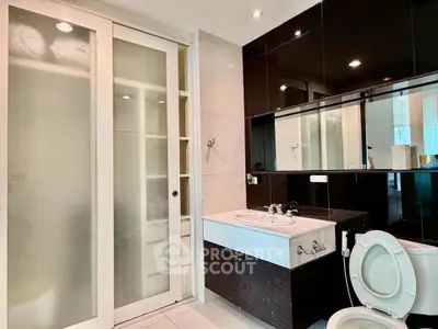 Modern bathroom with sleek black and white design, featuring a sliding door and stylish fixtures.
