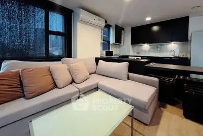 Modern living room with cozy sectional sofa and sleek kitchen in open layout apartment.