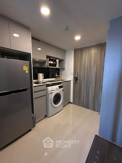 Modern compact kitchen with washing machine and sleek appliances in a stylish apartment.