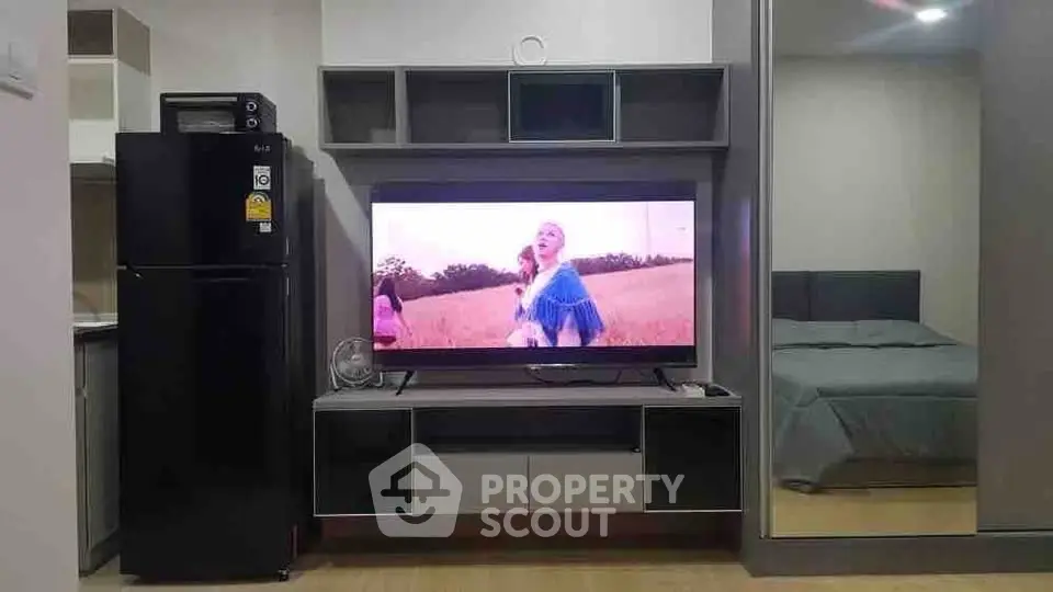 Modern living room with sleek entertainment center and adjacent kitchen area.