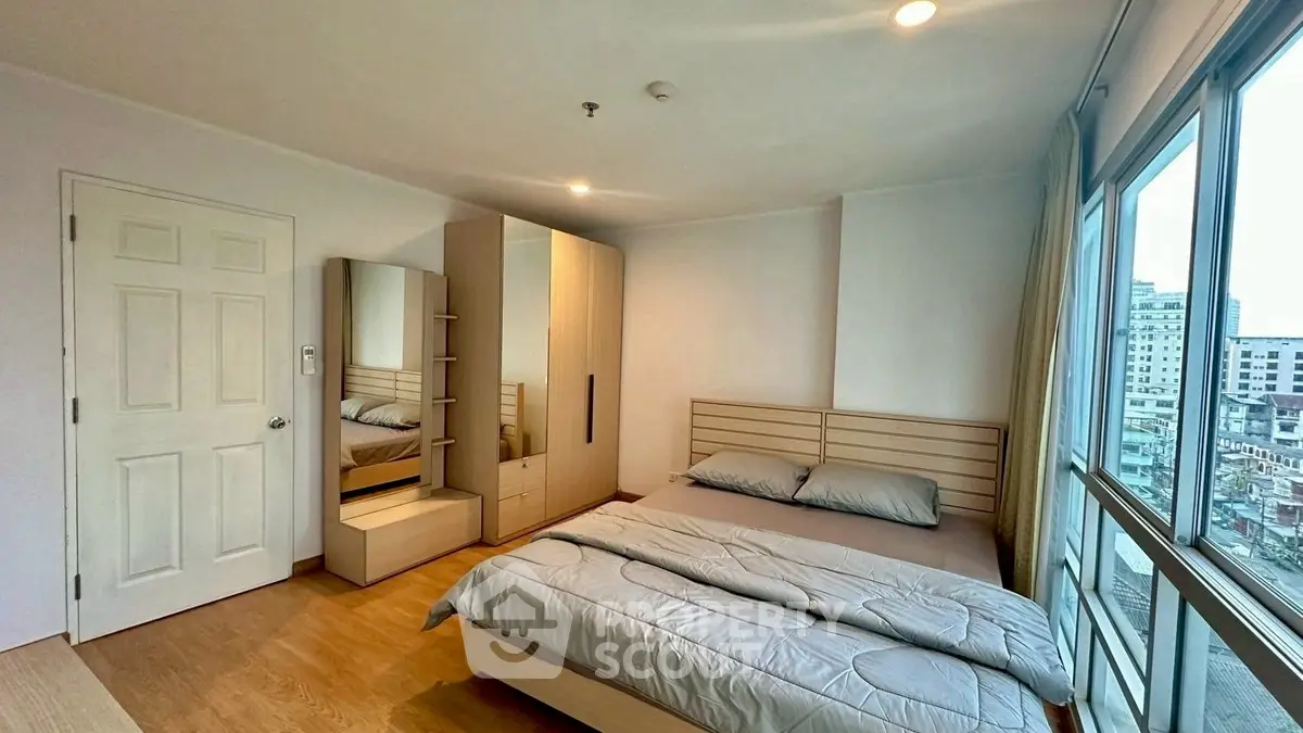 Modern bedroom with city view, featuring sleek furniture and ample natural light.