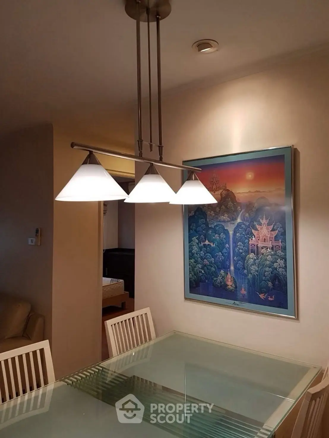 Elegant dining area with modern lighting and glass table, featuring artistic wall decor.