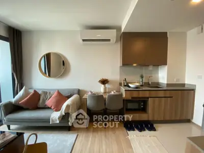 Modern living room with cozy sofa, dining area, and sleek kitchen in open layout apartment.