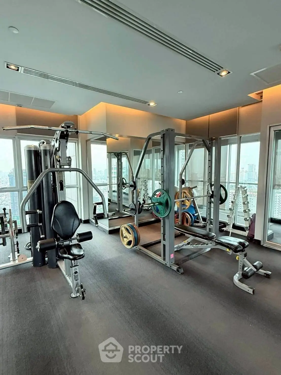 Modern gym with city view, featuring state-of-the-art fitness equipment in a high-rise building.