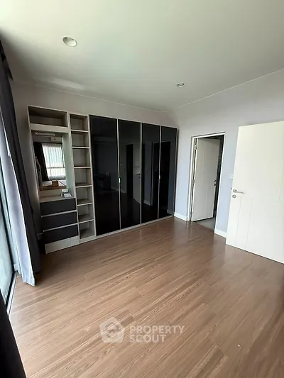 Spacious bedroom with sleek built-in wardrobe and wooden flooring