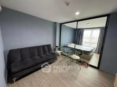 Modern studio apartment with cozy living area and bedroom separated by glass partition.