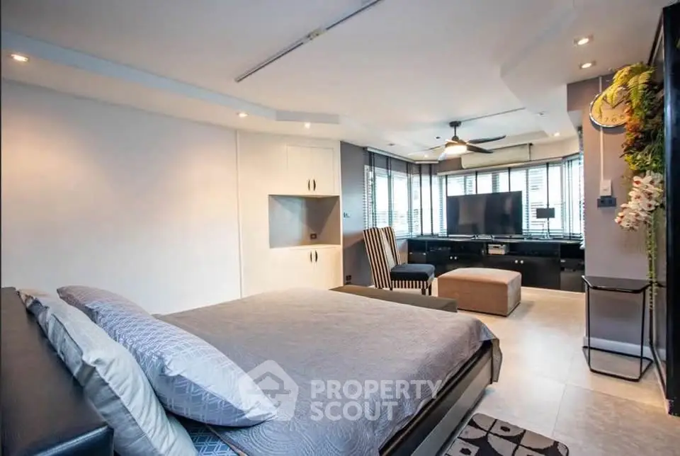Spacious modern bedroom with stylish decor and large windows for natural light.