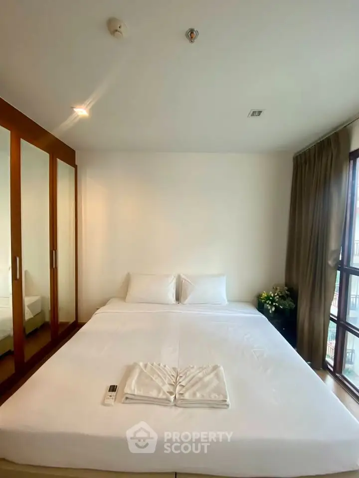 Cozy bedroom with large bed and mirrored wardrobe in modern apartment