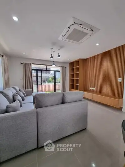Spacious modern living room with stylish grey sofas and wooden accent wall.
