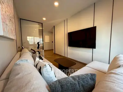 Modern living room with sleek design, large TV, and comfortable seating in a stylish apartment.