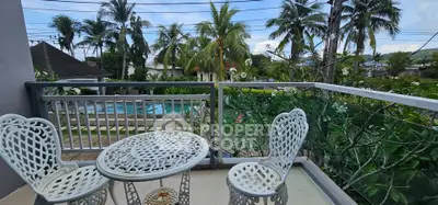Charming balcony with elegant white furniture overlooking lush garden and pool view.