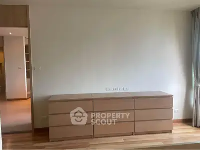 Spacious bedroom with modern wooden dresser and natural light