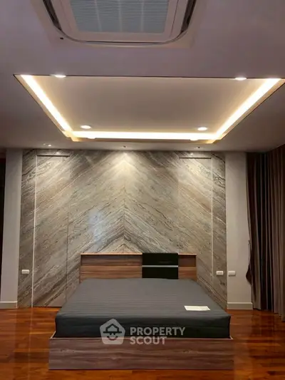 Luxurious modern bedroom with elegant wood flooring and stylish ceiling lights.