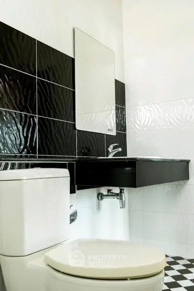 Modern bathroom with sleek black and white tiles and contemporary fixtures.