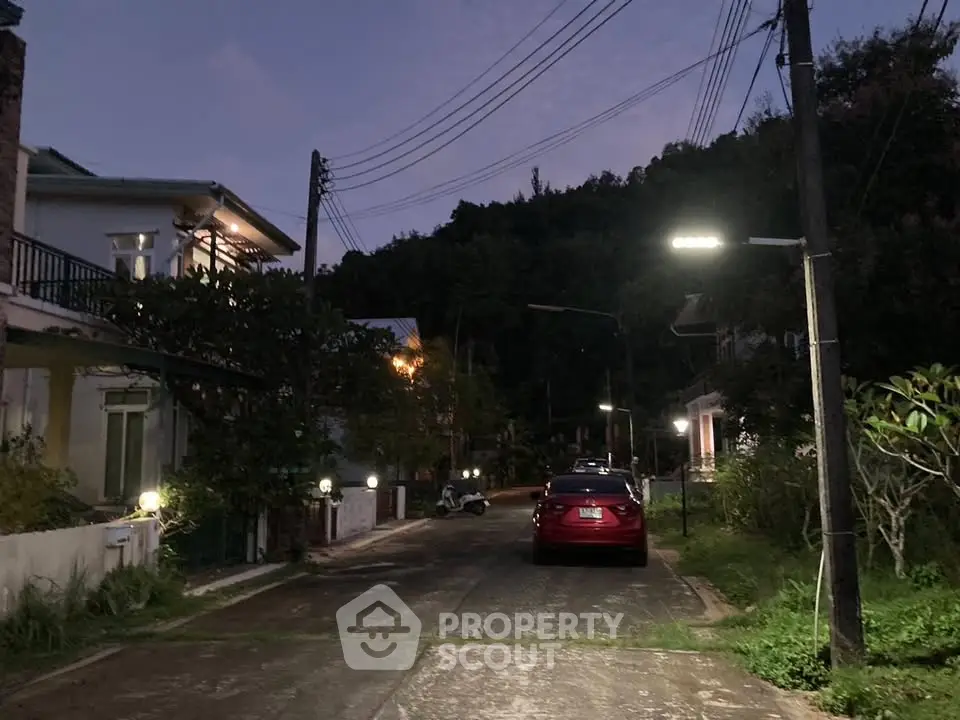 Charming residential street at dusk with cozy homes and streetlights, perfect for serene living.