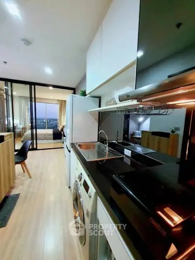 Modern kitchen with sleek appliances and open layout leading to a cozy living area with city view.